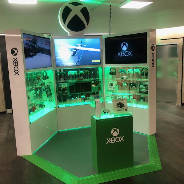 Microsoft Xbox branded retail display with green LED lighting, product showcases and overhead branding